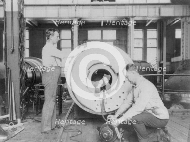 Three men working on large gun in Naval Gun Factory, Washington, D.C., one of the men lying..., 1903 Creator: Frances Benjamin Johnston.