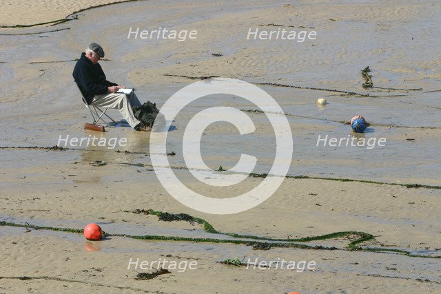 Man sitting on the sand in St Ives harbour at low tide, Cornwall