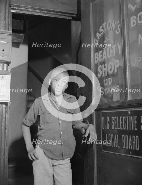 Youth waiting for a newspaper delivery truck, Washington, D.C., 1942. Creator: Gordon Parks.