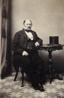 Studio portrait of a man at a table with a top hat, c1865. Artist: Unknown