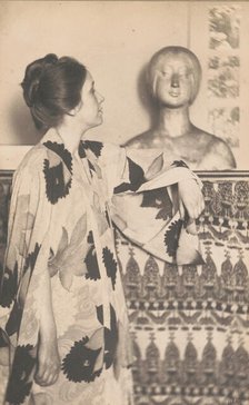 Woman wearing a kimono, standing, looking at a sculpted bust, c1900. Creator: Eva Watson-Schutze.