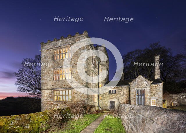 North Lees Hall from the south-east with the windows illuminated, Hathersage, Derbyshire, 2025.  Creator: Alun Bull.