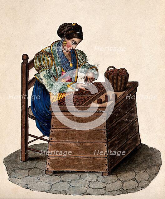 A woman sits at a wooden box counting money out of a basket onto a tray. Creator: Unknown.