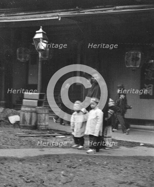 Man and two children crossing a street, Chinatown, San Francisco, between 1896 and 1906. Creator: Arnold Genthe.