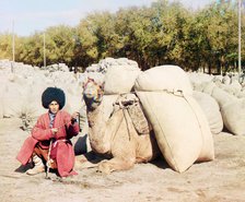 Turkmen man posing with camel loaded with sacks, probably of grain or cotton..., between 1905-1915. Creator: Sergey Mikhaylovich Prokudin-Gorsky.