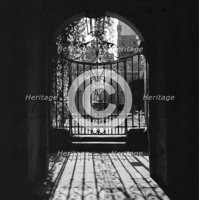 View through a decorative wrought iron gate in the Little Cloister at Westminster Abbey, 1946-1999. Creator: John Gay.