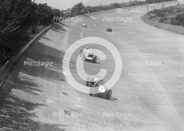 Freddie Dixon's Riley Red Mongrel Special leading RJ Munday's Munday Special, Brooklands, 1933. Artist: Bill Brunell.
