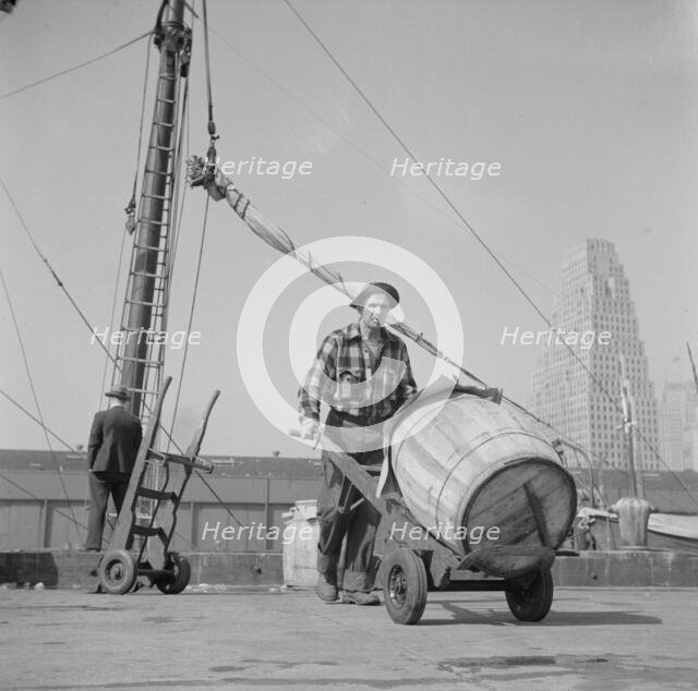 Dock stevedore at the Fulton fish market moving a barrel of codfish, New York, 1943. Creator: Gordon Parks.
