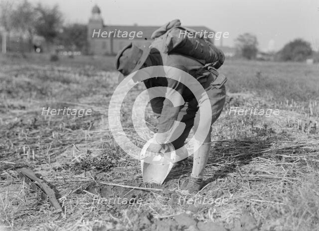 Leonard D. Mahon with steel helmet he invented that could be used as shovel, 1917. Creator: Harris & Ewing.
