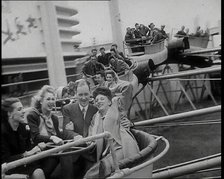 Male and Female Fairgroundgoers Riding in Gondolas Running Along Tracks on a Fairground..., 1938. Creator: British Pathe Ltd.