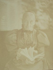 Elderly woman sitting in a chair holding a book, half-length portrait, facing front, c1890. Creator: Horace L Bundy.