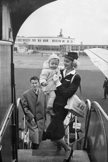 SAS stewardess carrying a baby onto a plane, Bulltofta airport, Malmö, Sweden, 1950. Artist: Torkel Lindeberg