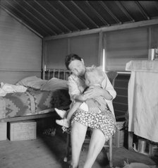 Mother from Oklahoma tends baby with dysentery, FSA camp, Tulare County, CA, 1939. Creator: Dorothea Lange.