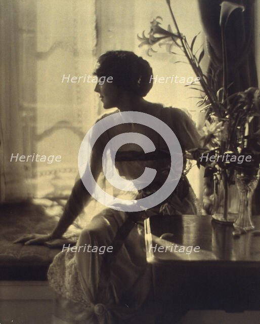 Woman sitting on window seat, looking left, full-length portrait, between 1900 and 1920. Creator: Unknown.