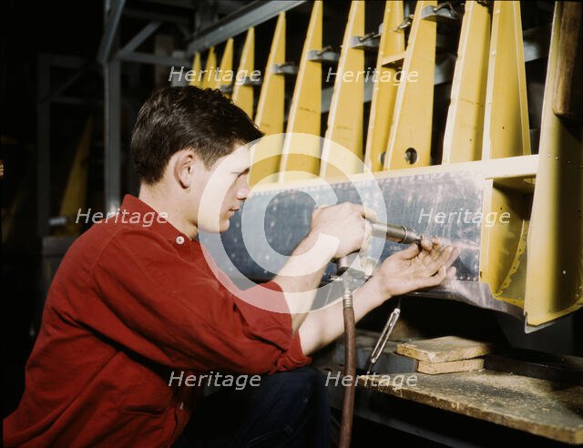 Riveter at work at the Douglas Aircraft Corporation plant in Long Beach, Calif., 1942. Creator: Alfred T Palmer.