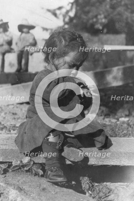 Young Eskimo child seated on board, between c1900 and c1930. Creator: Unknown.