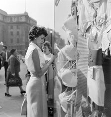 A young woman looking in the window of a lingerie shop in Piccadilly Circus, London, c1946-c1959. Artist: John Gay