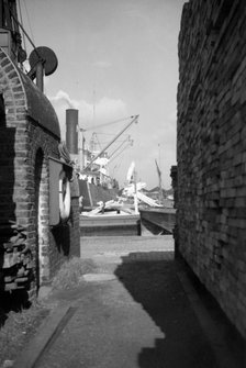 A view between harbour buildings in London docks, 1937. Artist: SW Rawlings
