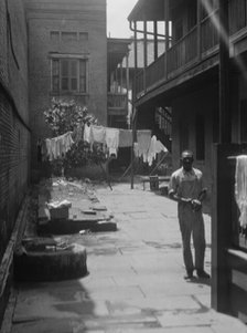 Man standing in a courtyard, New Orleans, between 1920 and 1926. Creator: Arnold Genthe.