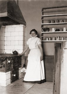 A maid, named Ruth, by the stove, 1905. Artist: Unknown