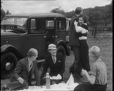 Male and Female Civilians Having a Picnic Beside a Car Whilst Two of Them Are Dancing, 1931. Creator: British Pathe Ltd.