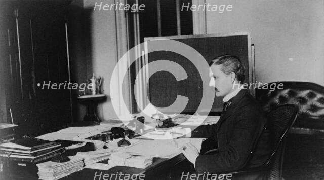 Dr. Miller, Treasury Department employee, half-length portrait, seated at..., between 1884 and 1930. Creator: Frances Benjamin Johnston.