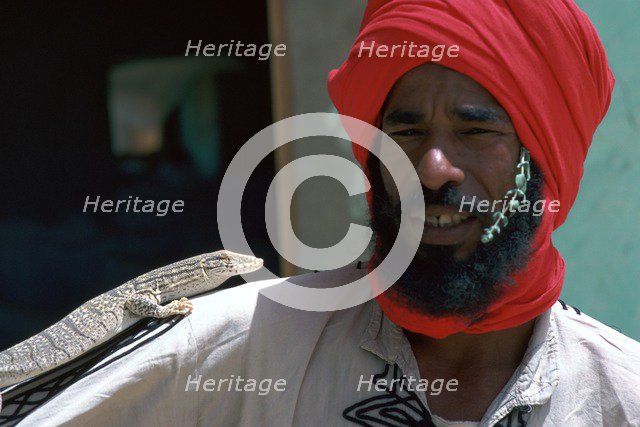 Keeper with a lizard in Tozeur zoo in Tunisia. Artist: Unknown