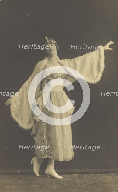 A prisoner of war in drag, wearing a dress and white cloak, poses...(between 1910 and 1919?). Creator: Albert Melzer.