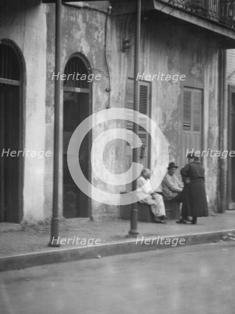 View from across street of people talking, New Orleans, between 1920 and 1926. Creator: Arnold Genthe.