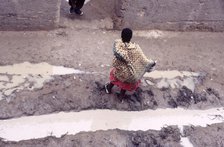 Woman in muddy street, Mopti, Mali, 1990. Creator: Amanda Waite.