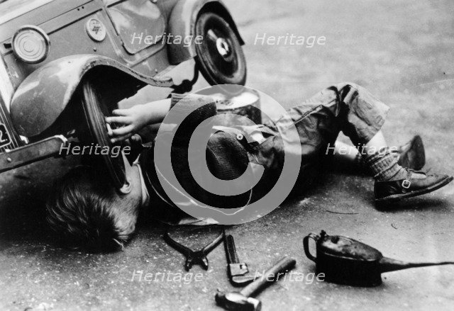 Michael Ware repairing his pedal car. Artist: Unknown