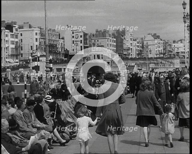 British Holidaymakers Walking Along the Promenade or Sitting on Deckchairs at Brighton..., 1938. Creator: British Pathe Ltd.