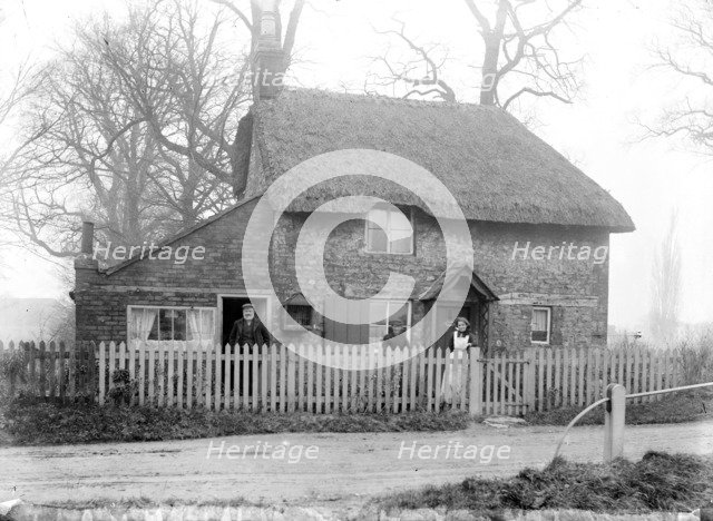 Thatched cottage with the inhabitants standing in the front garden, Uffington, Oxfordshire, 1916. Artist: Henry Taunt