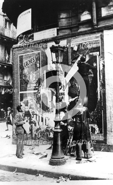 Billboard with men putting up propaganda posters, Paris, World War II, 1939-1945. Artist: Unknown