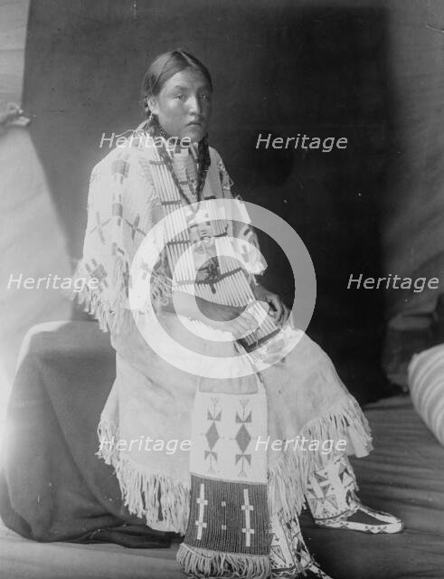 Red Elk Woman, a Sioux girl, full-length portrait, seated, facing right, c1907. Creator: Edward Sheriff Curtis.