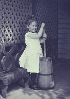 Little girl wearing white chemise, beaded necklace, and high-button shoes on porch with..., c1900. Creator: Unknown.