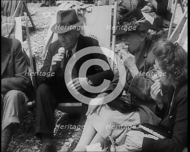 A Group of Two Men and Two Women Sitting on Deckchairs on the Beach at  Brighton and Eating..., 1939 Creator: British Pathe Ltd.