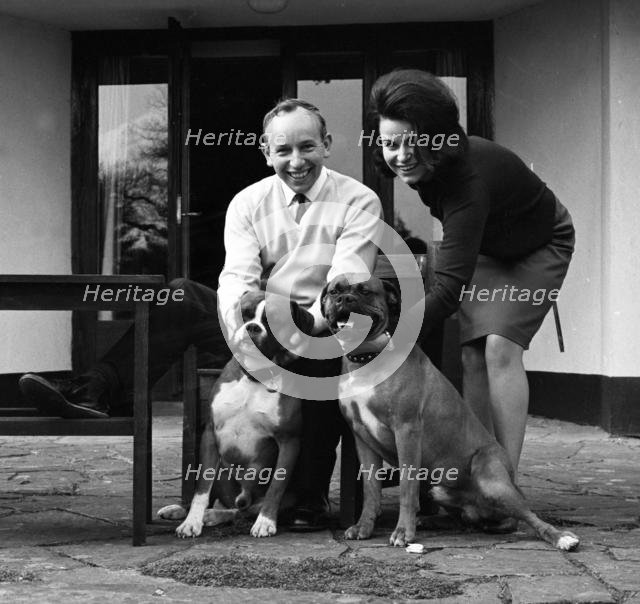 John Surtees relaxes at home with his wife and pet dogs in 1966. Creator: Unknown.
