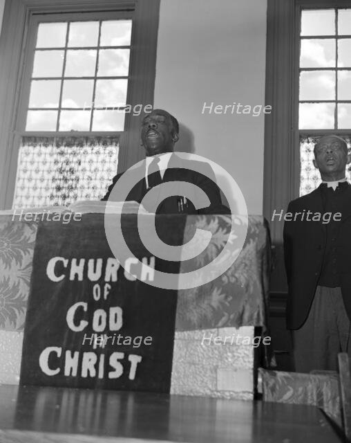 Elder Kelsey, pastor of the Church of God in Christ, opening a service..., Washington, D.C., 1942. Creator: Gordon Parks.