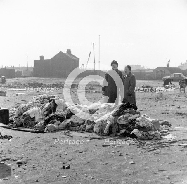Women standing by a pile of clothes at Rathbone Street Market, London, 1959. Artist: Henry Grant