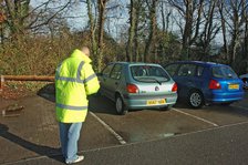 Car Park attendant recording car registration numbers. Artist: Unknown.