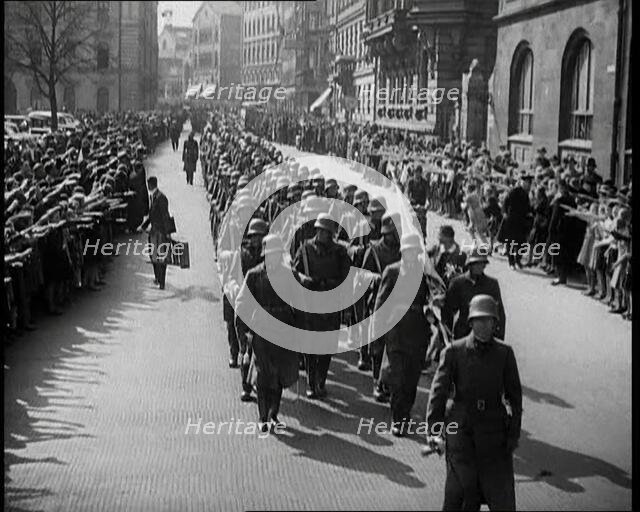 Crowd Watching German Soldiers Marching Down a Street Towards the Camera, 1930s. Creator: British Pathe Ltd.