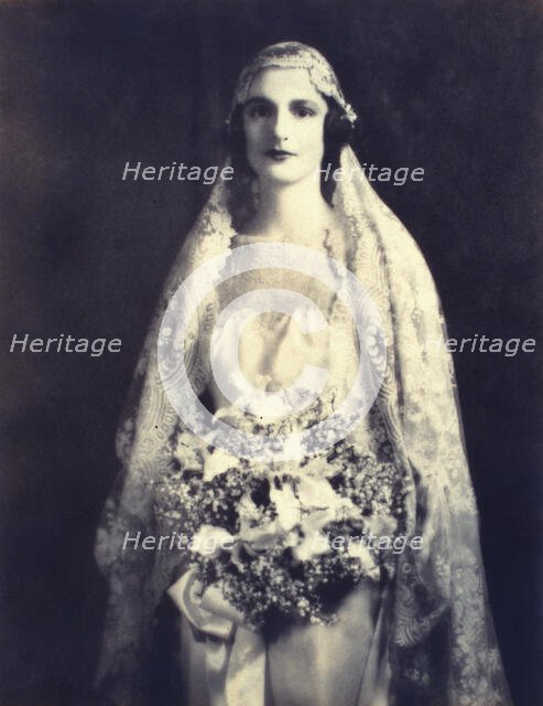 Bride holding a wedding bouquet, facing front, three-quarter length portrait, between 1920 and 1930. Creator: Unknown.