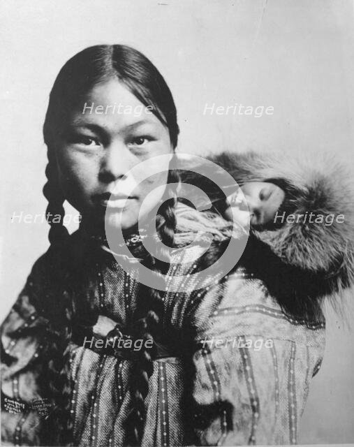 Eskimo mother with child on back, c1906. Creator: Lomen Brothers.