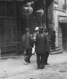 Men standing or walking down a sidewalk, Chinatown, San Francisco, between 1896 and 1906. Creator: Arnold Genthe.