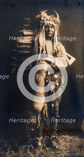 A Piegan man, Iron Breast, in ceremonial dress, 1900. Creator: Edward Sheriff Curtis.