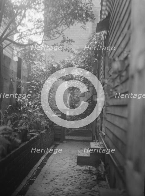 View down narrow outdoor passageway, New Orleans or Charleston, South Carolina, c1920-1926. Creator: Arnold Genthe.