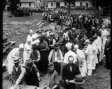 American Civilians Serving Meals for a Large Crowd on a Queue Outdoors, 1930. Creator: British Pathe Ltd.