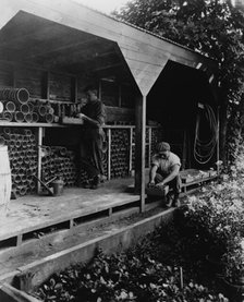 Gardeners potting plants in a shed, posed to...Rudyard Kipling's poem The Glory of the Garden, 1917. Creator: Frances Benjamin Johnston.