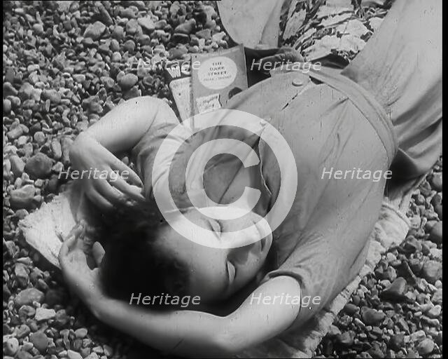 A Young Woman Lying on the Beach at  Brighton With Her Eyes Closed With a Two Books to the..., 1939. Creator: British Pathe Ltd.